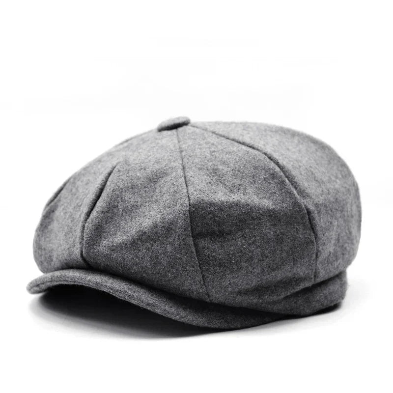 Gray wool newsboy cap with button top and stitched panels on white background