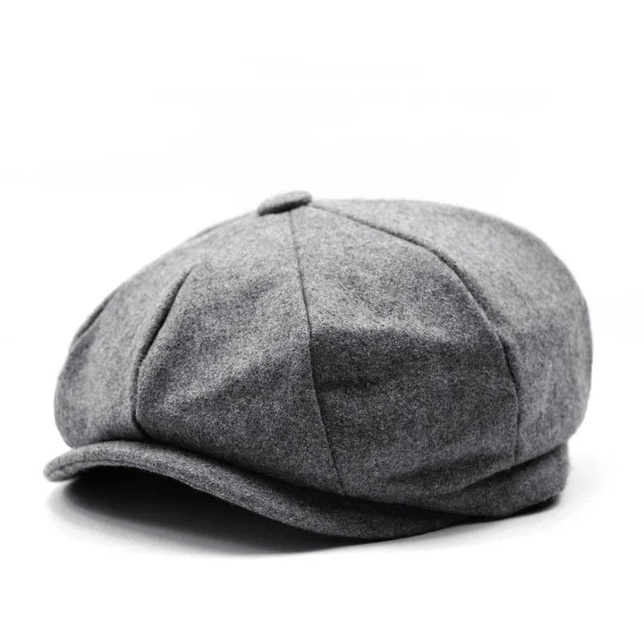 Gray wool newsboy cap with button top and stitched panels on white background