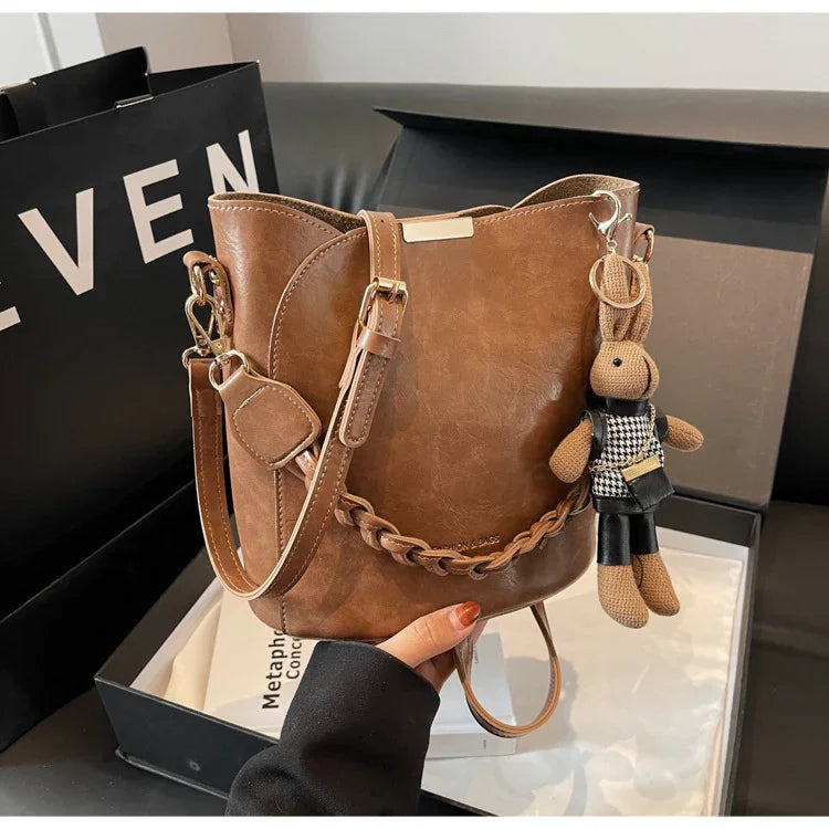 Brown leather bucket handbag with braided detail and bunny keychain in black and white outfit