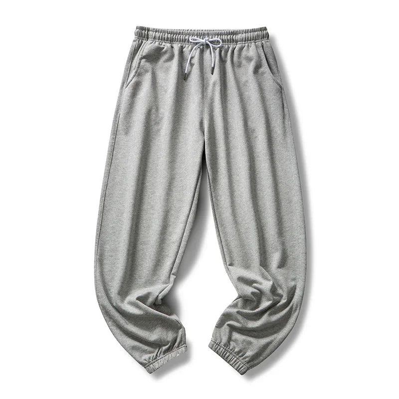 Light gray sweatpants with elastic waistband, drawstring, side pockets, and cuffed ankles