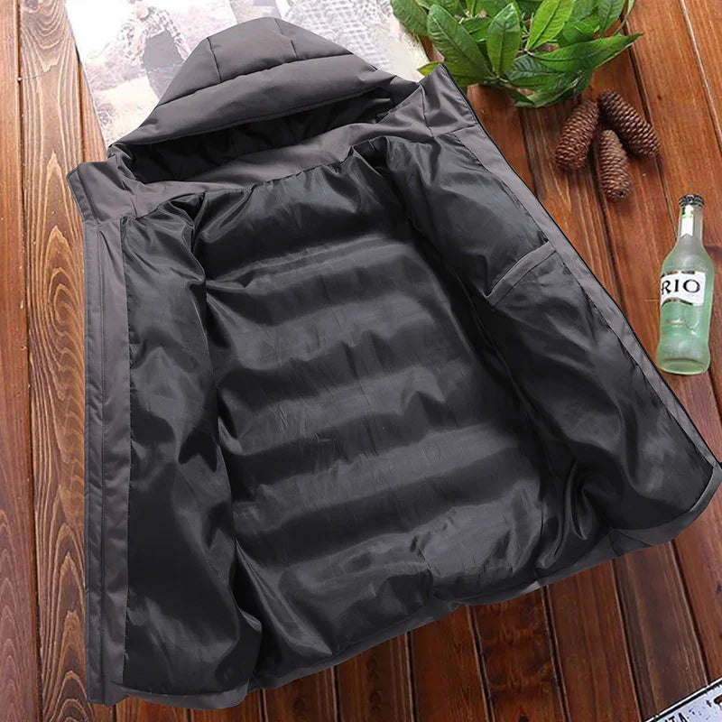 Black insulated winter jacket with hood open flat on wooden surface with decorative pinecones and bottle