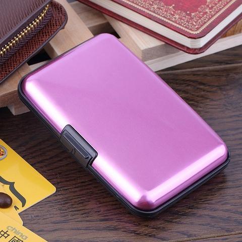 Compact metallic pink card holder wallet on wooden table near books and cards
