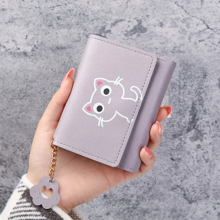 Hand holding a lavender compact wallet with cute cartoon cat design and flower keychain