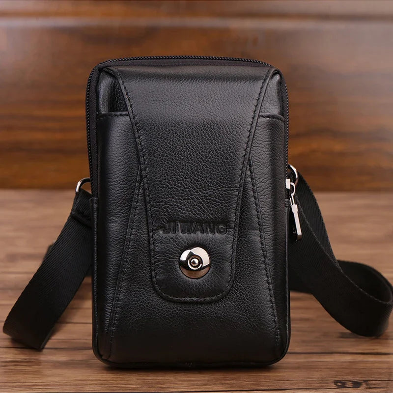 Black leather small crossbody bag with flap and metal button closure on wooden surface