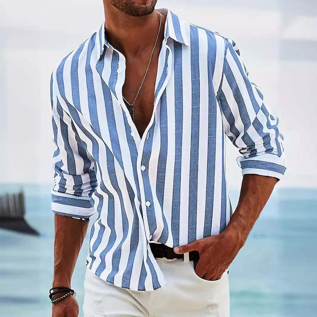 Man wearing blue and white vertical striped casual shirt with rolled sleeves by the sea