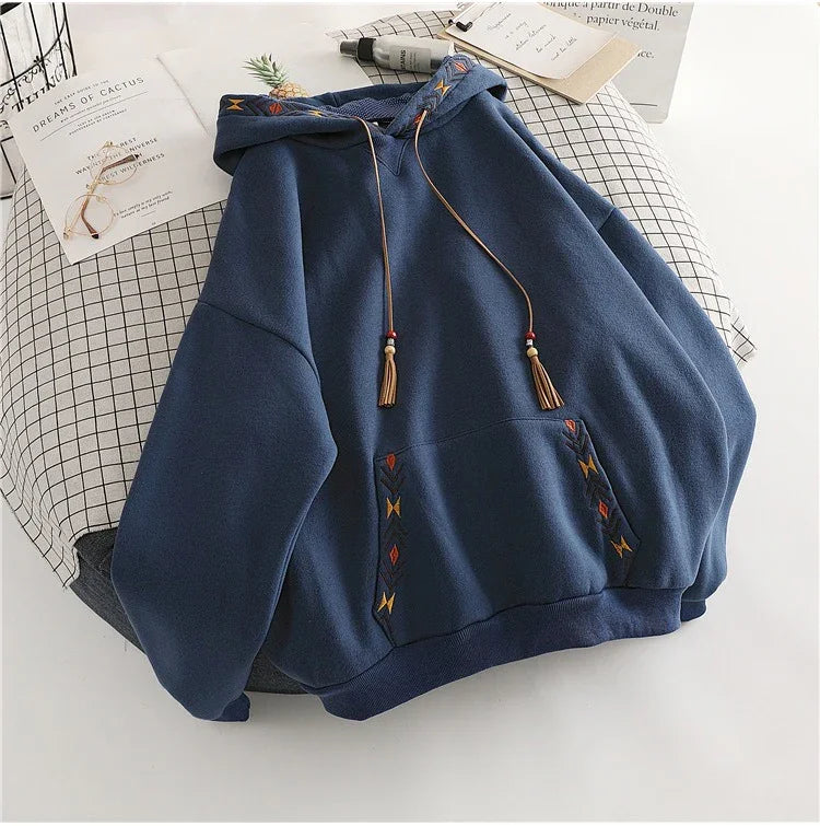 Blue hoodie with embroidered geometric patterns and tasseled drawstrings on grid-patterned cloth