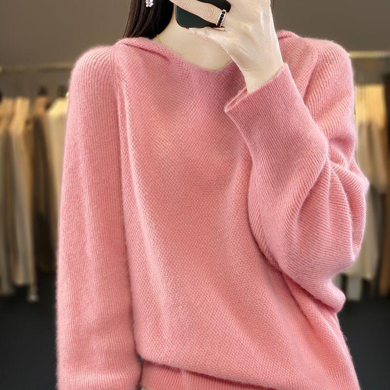 Close-up of a person wearing a soft pink wool sweater, taking a mirror selfie indoors