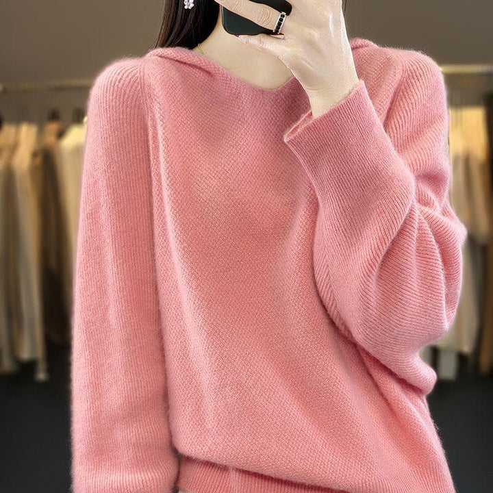 Close-up of a person wearing a soft pink wool sweater, taking a mirror selfie indoors