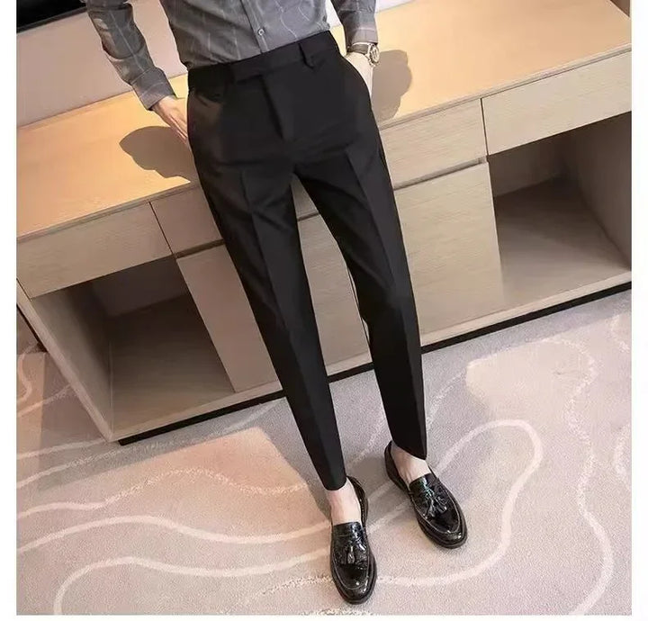 Man wearing slim fit black dress pants with black tassel loafers and gray shirt, standing indoors