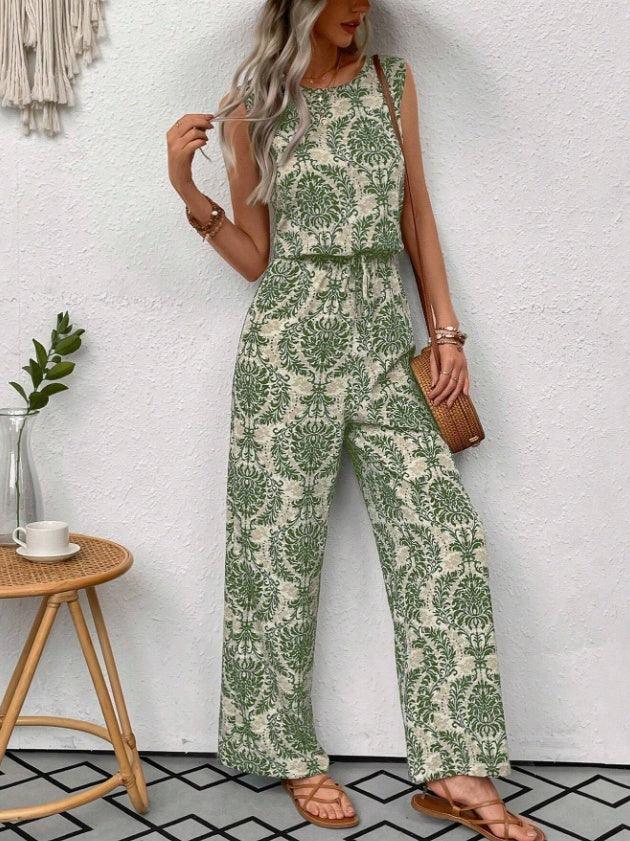 Woman wearing sleeveless green and beige printed wide-leg jumpsuit with sandals and wicker crossbody bag