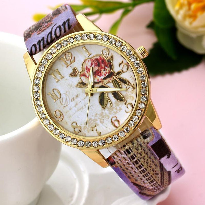 Gold wristwatch with rhinestone bezel, floral dial design, and printed London-themed fabric strap
