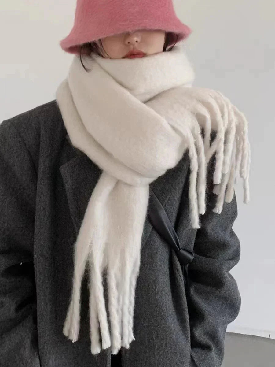 Woman wearing a pink bucket hat, oversized white wool scarf with fringes, and dark gray coat