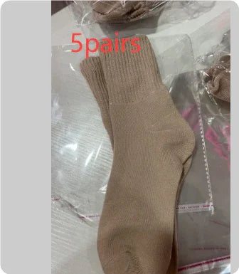 Beige ribbed knit socks laid on plastic packaging with 5 pairs label, casual footwear