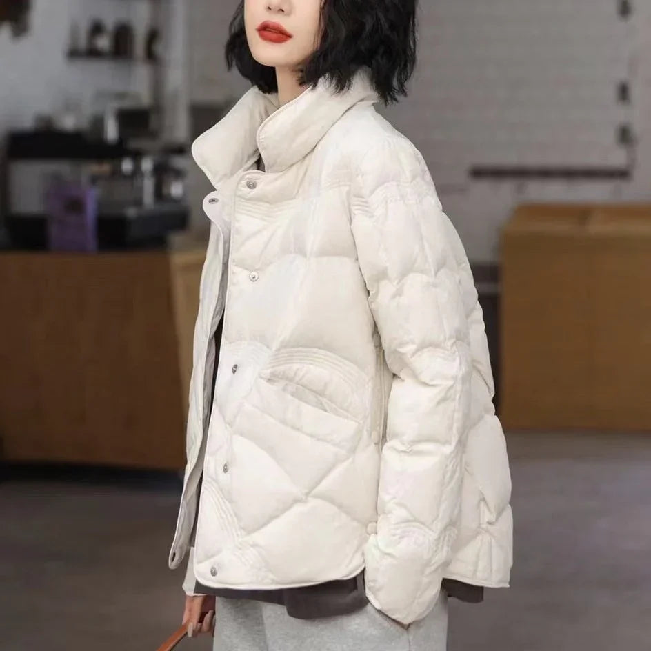 Woman in stylish white padded winter jacket with high collar in indoor modern setting