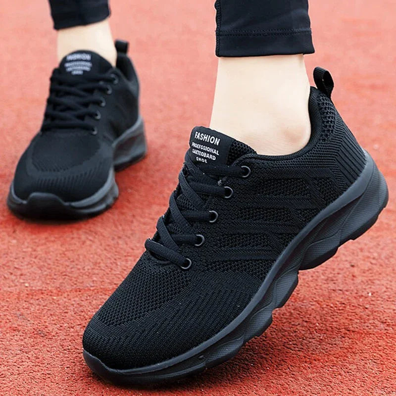 Black lightweight knit sneakers with lace-up design and cushioned sole on red track surface