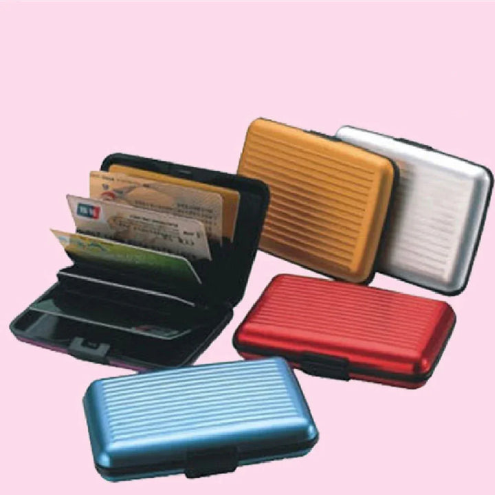 Compact aluminum card holders in blue, red, gold, and silver with black interior on pink background
