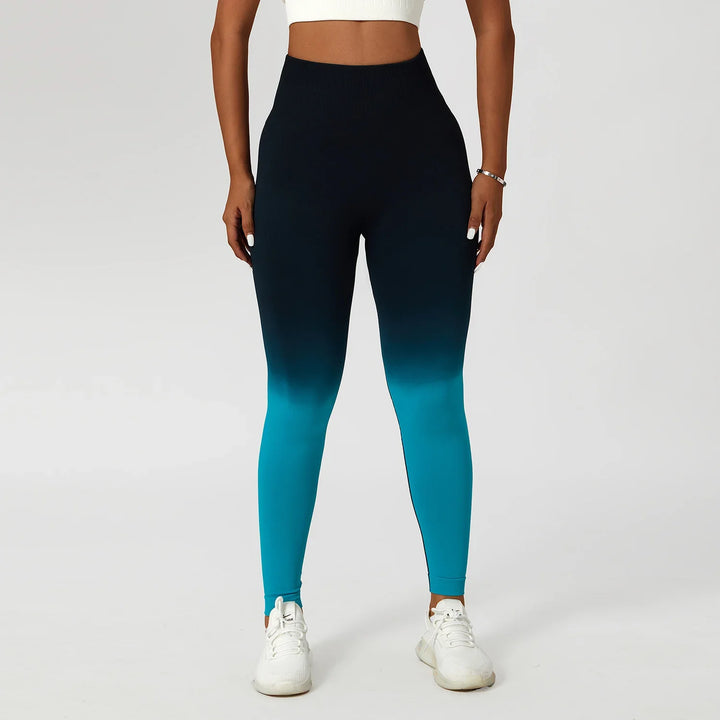 Woman in blue ombre high-waisted leggings and white crop top against plain background