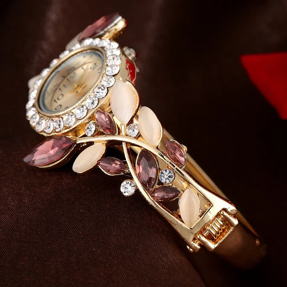 Elegant gold wristwatch with crystal-studded bezel and leaf-shaped purple and white gemstone accents on band
