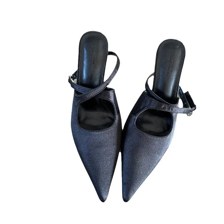 pair of black pointed toe slingback flats with strap and buckle on white background