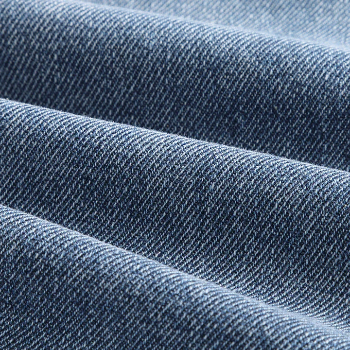 Close-up texture of blue denim fabric showing detailed weave and diagonal pattern