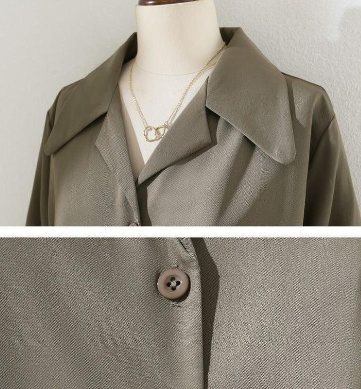 Close-up of olive green buttoned jacket on mannequin with wide collar and gold chain necklace