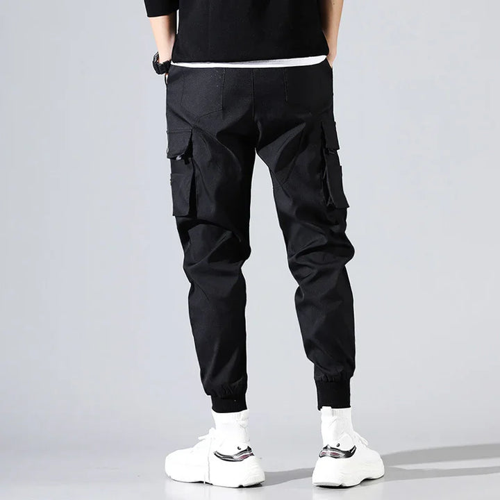 Back view of person wearing black cargo jogger pants with side pockets and white sneakers
