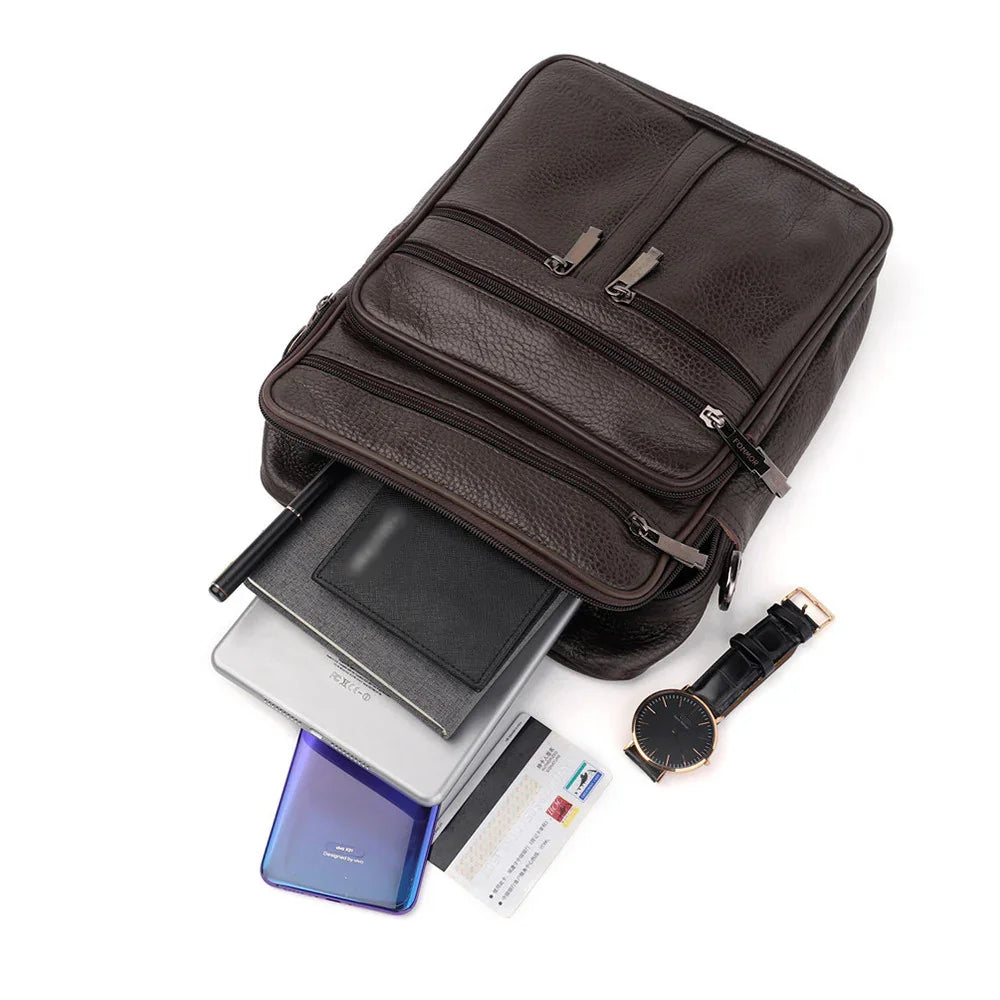 dark brown leather backpack with multiple zippered compartments and essentials like watch, cards, phone, tablet