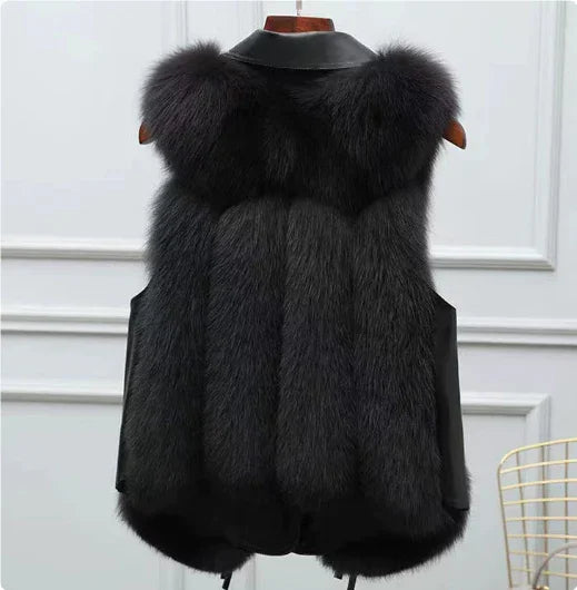 black faux fur vest with leather collar hanging on wooden hanger against white paneled wall