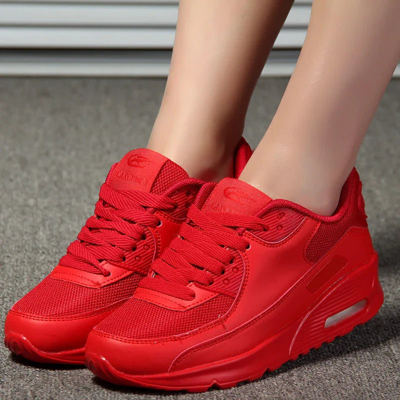 Bright red sporty sneakers with mesh and leather panels worn on feet on gray carpet