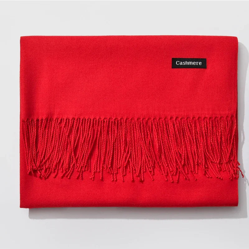 Bright red cashmere scarf with fringe tassels, folded on white background