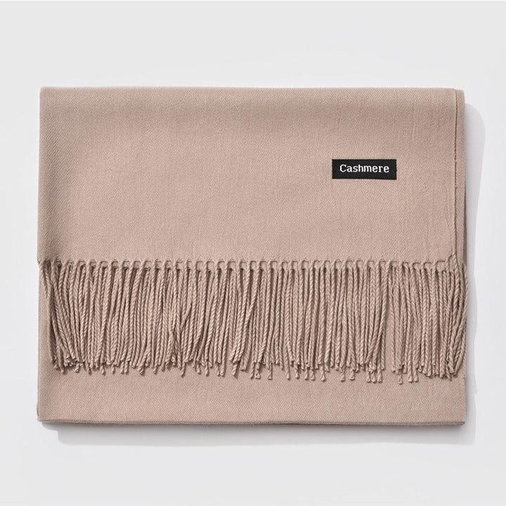 Beige cashmere scarf with fringe edges and black label on white background