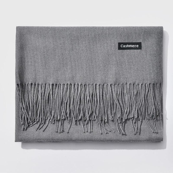 Folded gray cashmere scarf with fringed edges and a black label reading 'Cashmere'