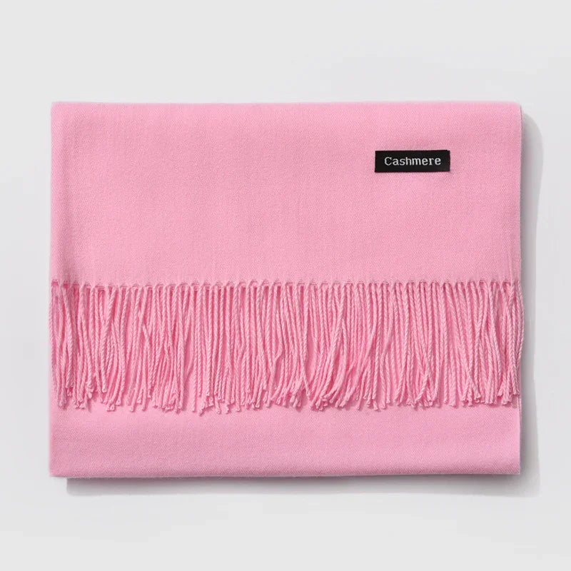 Soft pink cashmere scarf with fringed edges folded on white background