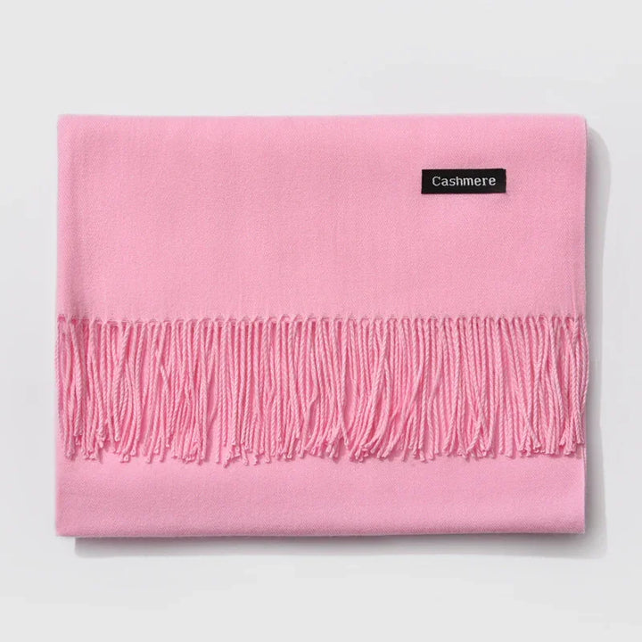 Soft pink cashmere scarf with fringed edges folded on white background