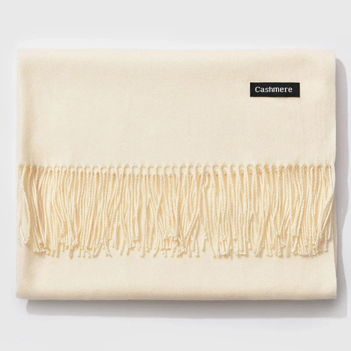 Soft ivory cashmere scarf with fringed edges and a black label on a white background