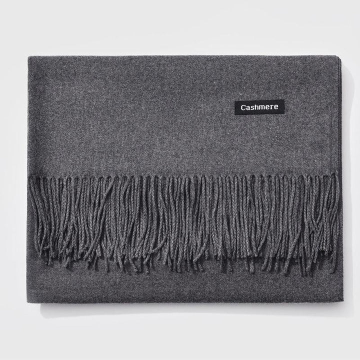 Folded dark gray cashmere scarf with fringed edges on white background