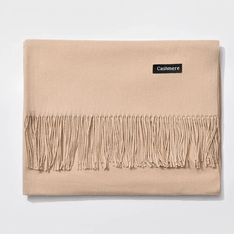 Beige cashmere scarf with fringed edge and black label on white background