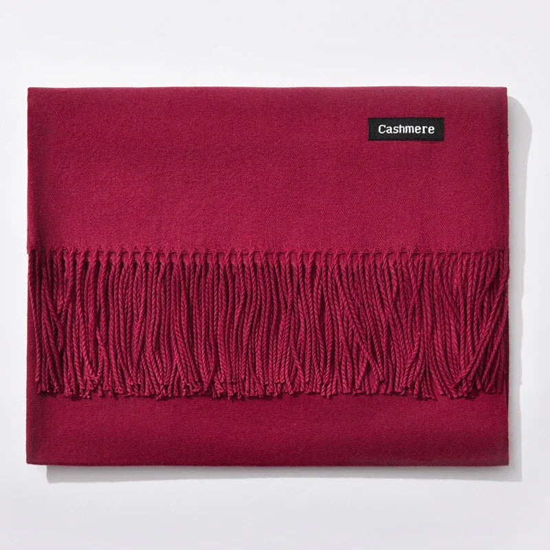 Folded red cashmere scarf with fringes and black cashmere label on white background