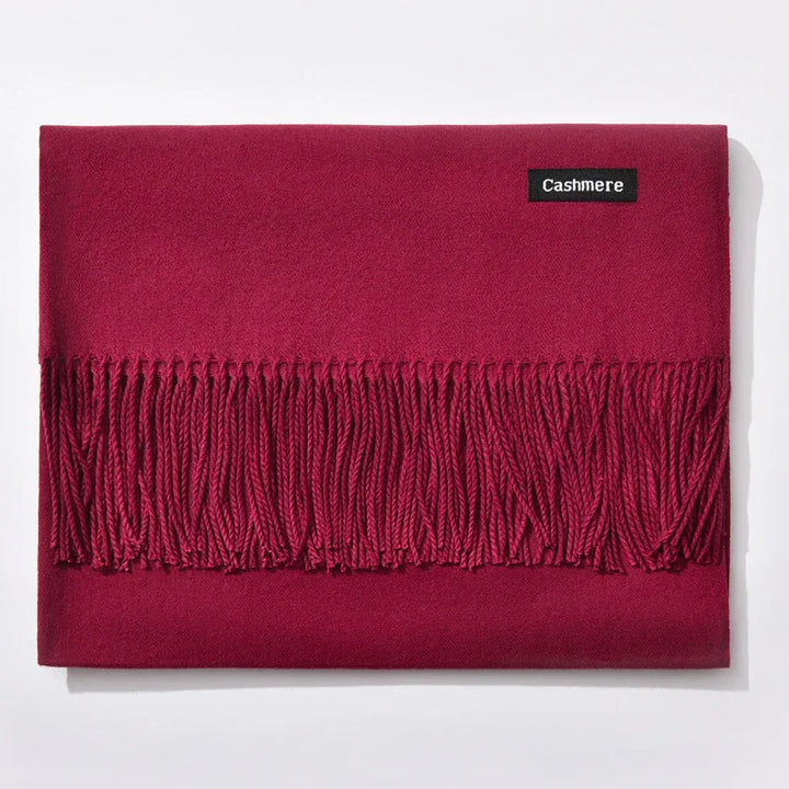 Folded red cashmere scarf with fringes and black cashmere label on white background
