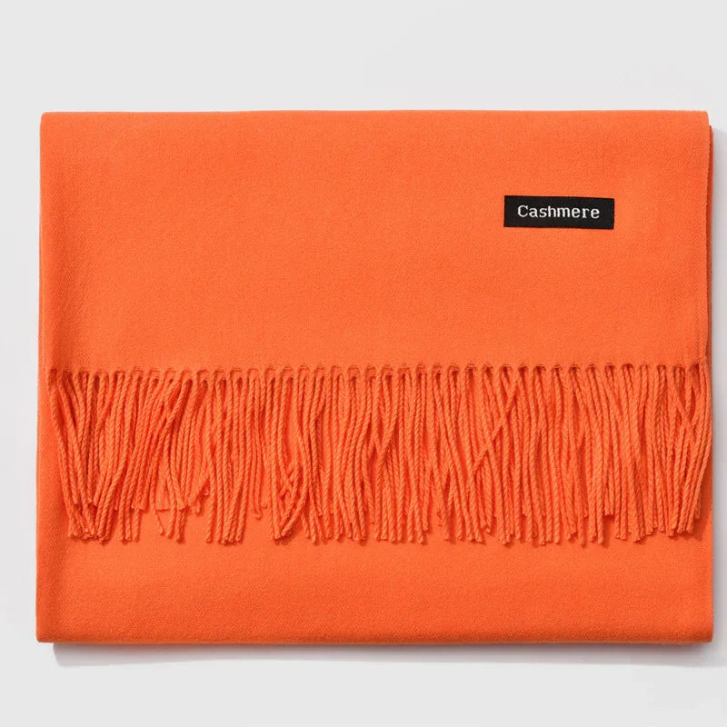 Folded bright orange cashmere scarf with fringed edge on white background