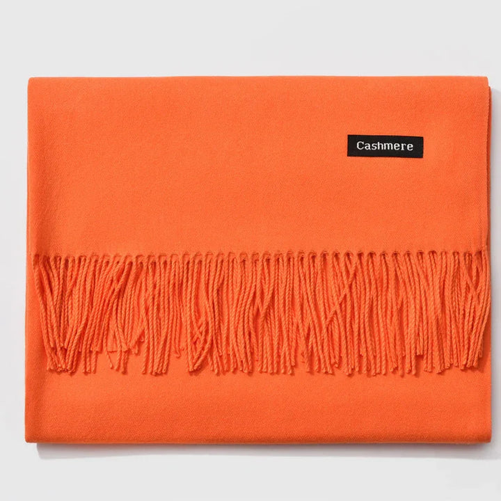 Folded bright orange cashmere scarf with fringed edge on white background