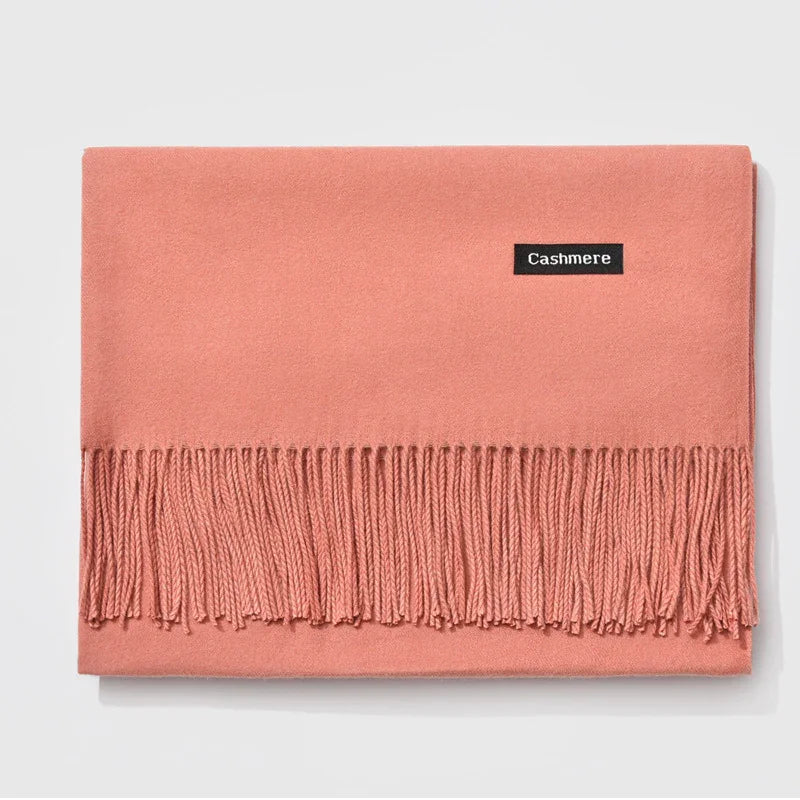 Soft pink cashmere scarf with fringe detailing laid flat on white background