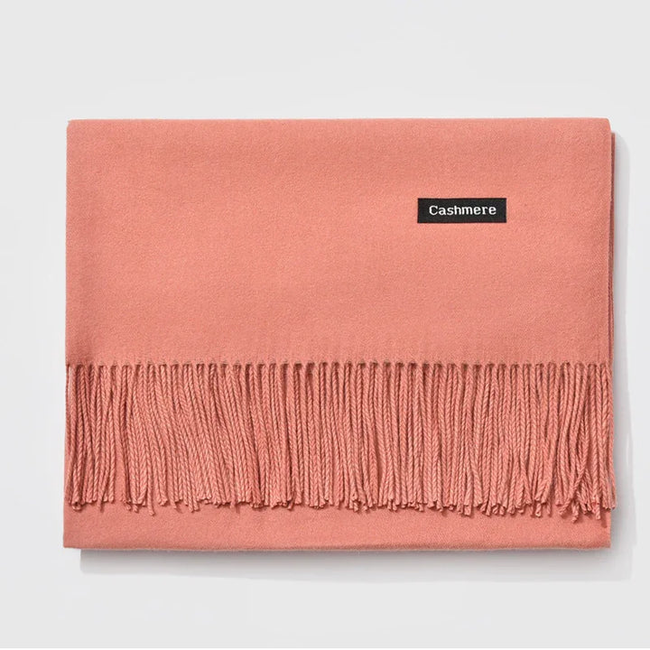 Soft pink cashmere scarf with fringe detailing laid flat on white background
