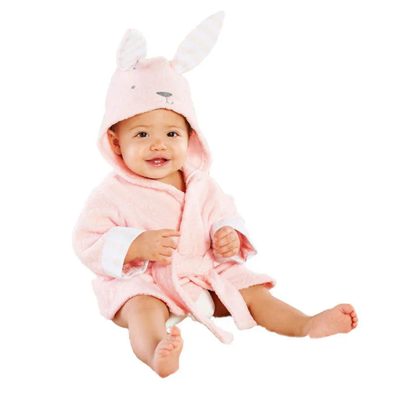 Smiling baby wearing pink hooded bunny robe with ears, sitting on white background