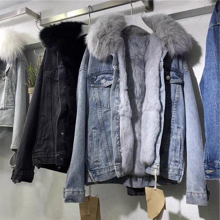 Denim jackets with fluffy fur collars in black, grey, and light blue hanging on a metal rack against a white wall