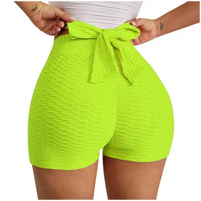 Woman wearing neon green textured high waisted shorts with bow tie detail