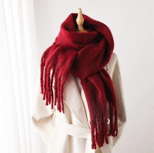 Warm thick red wool scarf with fringes displayed on mannequin wearing beige coat