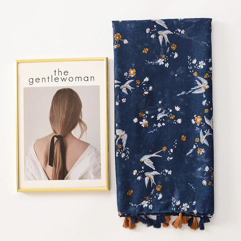 Framed artwork of a woman with tied hair next to blue floral bird patterned fabric with tassels