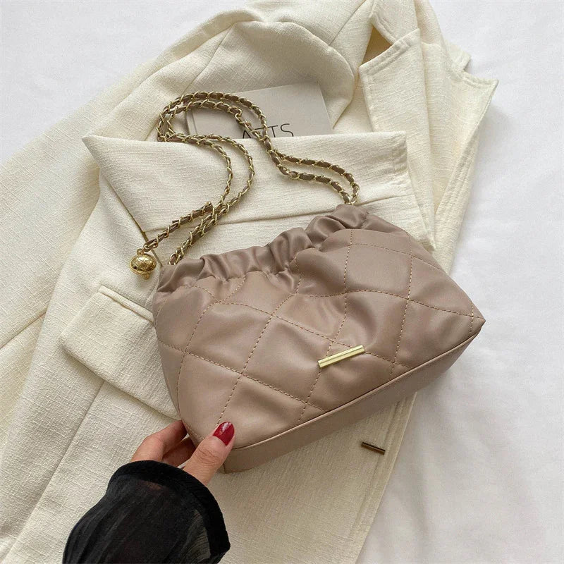 Taupe quilted shoulder bag with gold chain strap on cream textured blazer