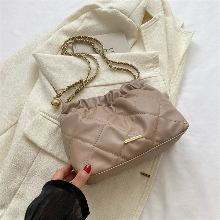 Taupe quilted shoulder bag with gold chain strap on cream textured blazer